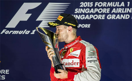 Ferrari's German driver Sebastian Vettel kisses the trophy on the podium after winning the Formula One Singapore Grand Prix in Singapore on September 20, 2015. (AFP)