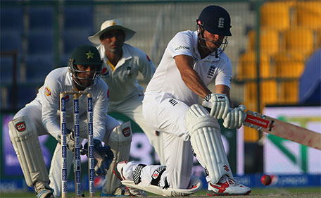 England's Alastair Cook (right) is watched by Pakistan's wicketkeeper Sarfraz Ahmed (left) and fielder Younis Khan as he plays a shot during the second day's play of the first cricket Test match between Pakistan and England at The Sheikh Zayed International Cricket Stadium in Abu Dhabi on October 14, 2015. (AFP)