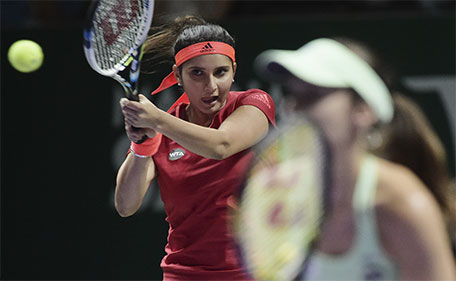 Sania Mirza (left) of India makes a forehand return as she and her partner  Martina Hingis of Switzerland play Garbine Muguruza and Carla Suarez Navarro, both of Spain and during the doubles final at the WTA tennis finals in Singapore on Sunday, Nov. 1, 2015.  (AP)