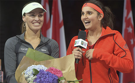 Sania Mirza (right) of India accompanied by her partner Martina Hingis of Switzerland, speaks at a ceremony to receive their trophy after winning the doubles event at the WTA tennis finals in Singapore Sunday, Nov. 1, 2015. (AP)