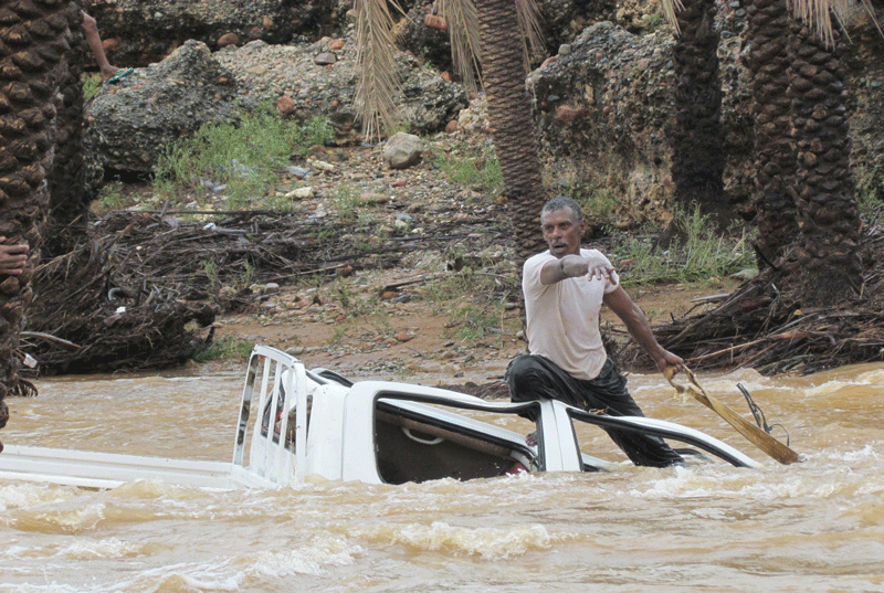 A man gestures as he tries to save a vehicle swept away by flood waters in Yemen's island of Socotra on November 2, 2015. (Reuters)