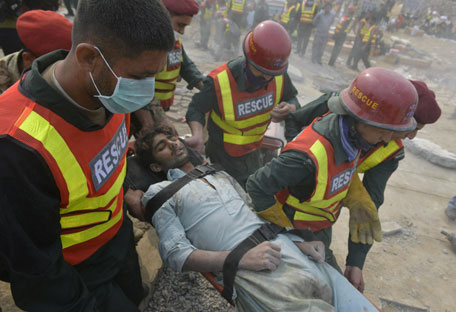 Pakistani rescuers move a man rescued from under the rubble of a collapsed factory on the outskirts of Lahore on November 5, 2015.  (AFP)
