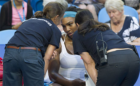 Serena Williams of the US is examined by medical staff for a knee injury before retiring injured against Jamila Wolfe of the Australia Gold team during their sixth session women's singles match on day three of the Hopman Cup tennis tournament in Perth on January 5, 2016.  (AFP)