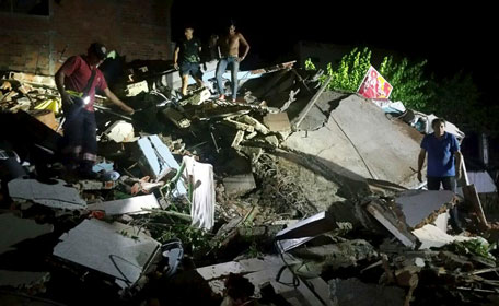 People stand next to the debris of a building after a 7.8 magnitude earthquake struck off the country's northwest Pacific coast causing "considerable damage", in Manta, Ecuador. (Reuters)