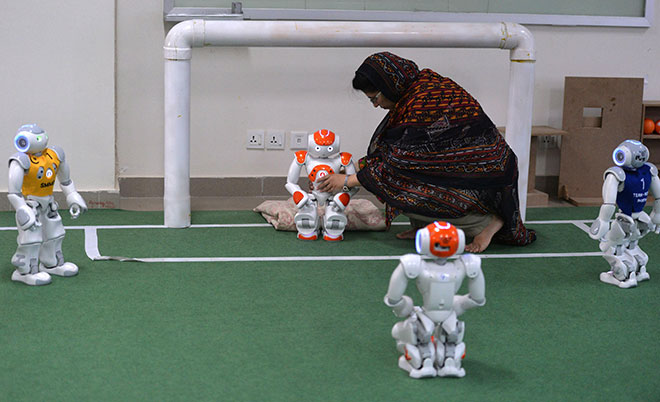 In this photograph taken on May 9, 2016, a Pakistani student and team member of Robotics and Intelligence Systems Engineering (RISE) places robot football players in the engineering department of the National University of Sciences and Technology in Islamabad. (AFP)