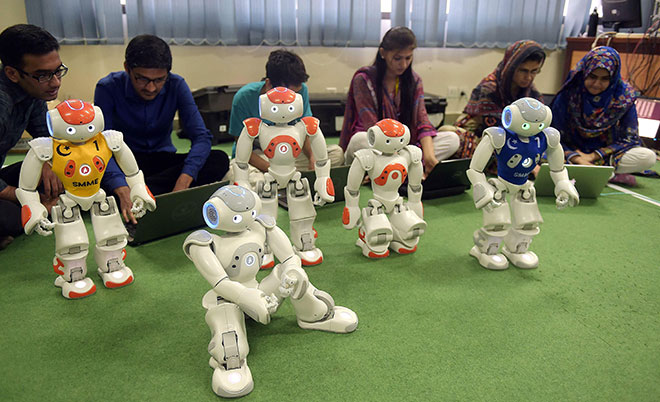 In this photograph taken on May 9, 2016, Pakistani students and team members of Robotics and Intelligence Systems Engineering (RISE) programme their robot football players in the engineering department of The National University of Sciences and Technology in Islamabad. (AFP)