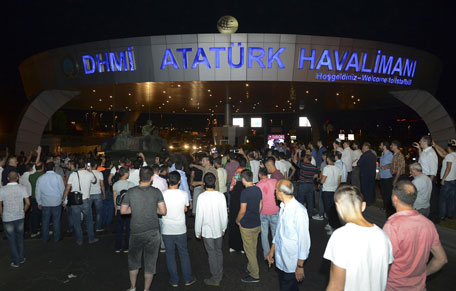 People stand in front of a tank parked in the entrance to Istanbul's Ataturk airport, early Saturday, July 16, 2016. (AP)