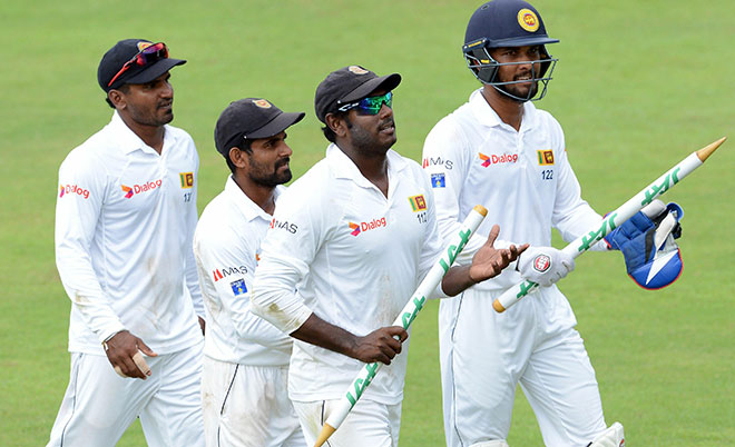 Sri Lanka's captain Angelo Mathews (centre) and teammates leave the grounds with the stumps after victory in the opening Test match between Sri Lanka and Australia at the Pallekele International Cricket Stadium in Pallekele on July 30, 2016. (AFP)